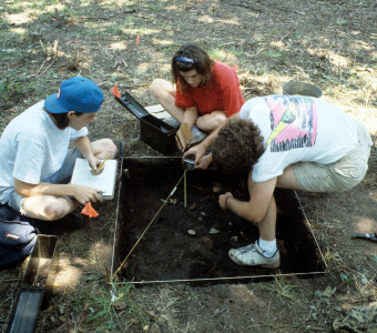 Students measure and record the depth at which each artifact was uncovered during excavation of their 1x1 meter square unit at the Quarry Creek site (1991)