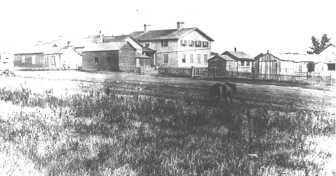 View of the back side of the two-storey historic Fort Riley Hospital and surrounding buildings.