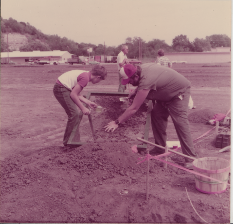 Community volunteers, Les Esry and his son, screening dirt at the Holidome site.